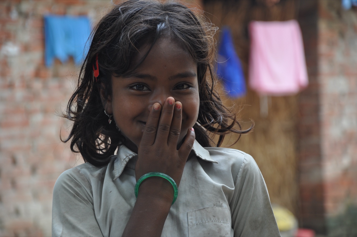 A girl from Masauli village smiling shyly behind her hand